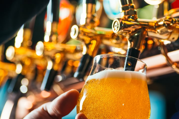 Close up of bartender pouring fresh draft beer into a glass from beer taps in a pub or bar.