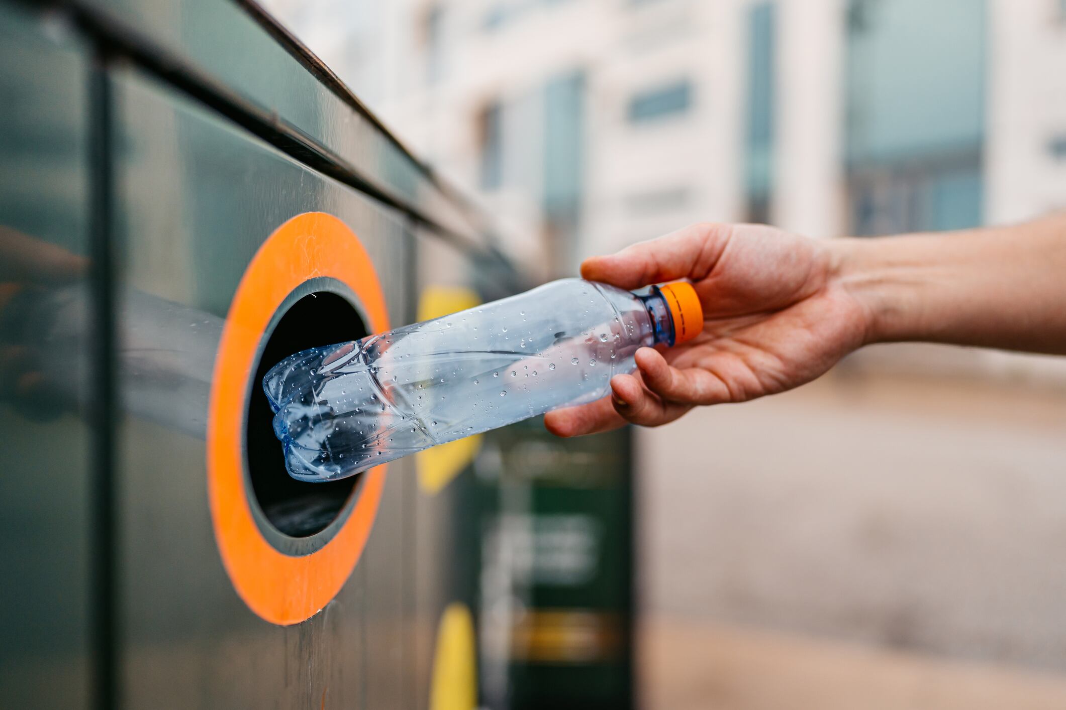 Close-up of a young man putting a water bottle in a recycling bin in Malmo in Sweden.