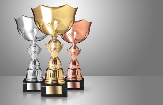 golden, silver and bronze trophies on gray background