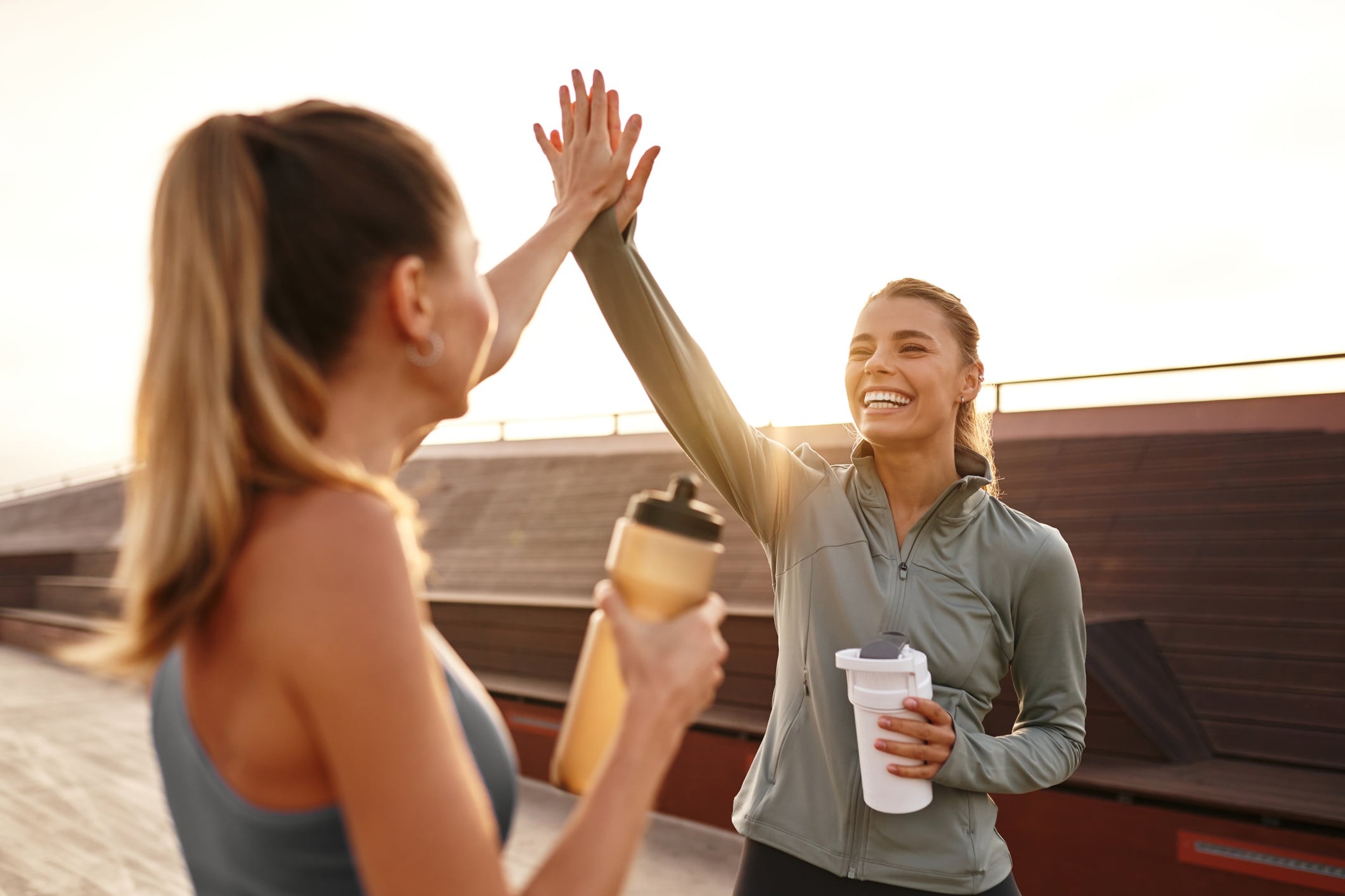 Two women celebrate finishing a workout with a high-five.