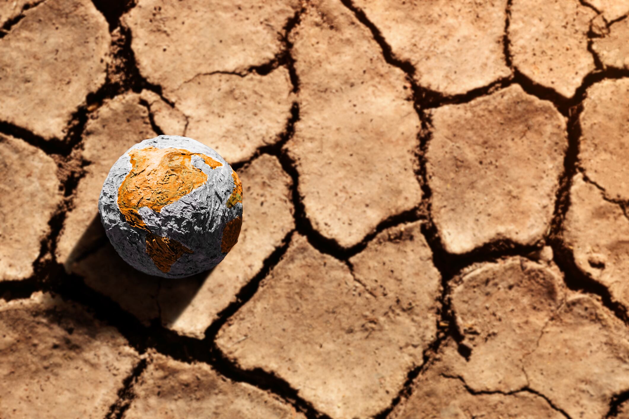 Water Crisis, Climate Change, El Nino, Global Warming Issue Concept. Brown Globe lay on Cracked Dry Soil Ground. Land without Water. High Temperature on Hot Sunny Day