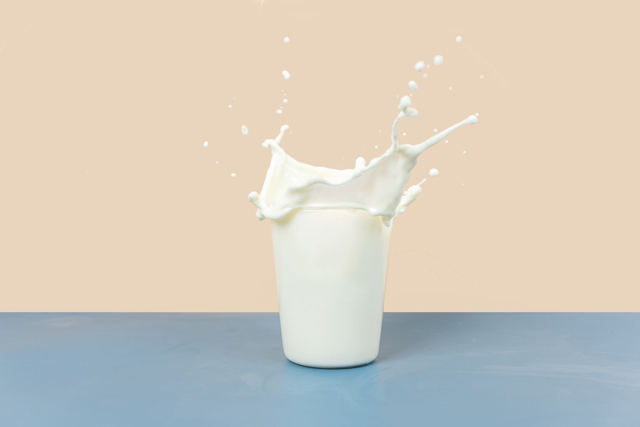 The splashing milk in the cup is against a yellow and gray background