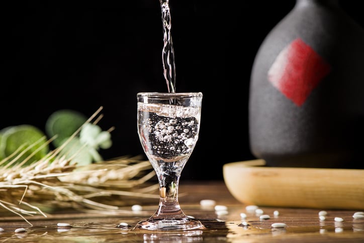 chinese liquor spirits drink is poured into a glass from a bottle on wood background
