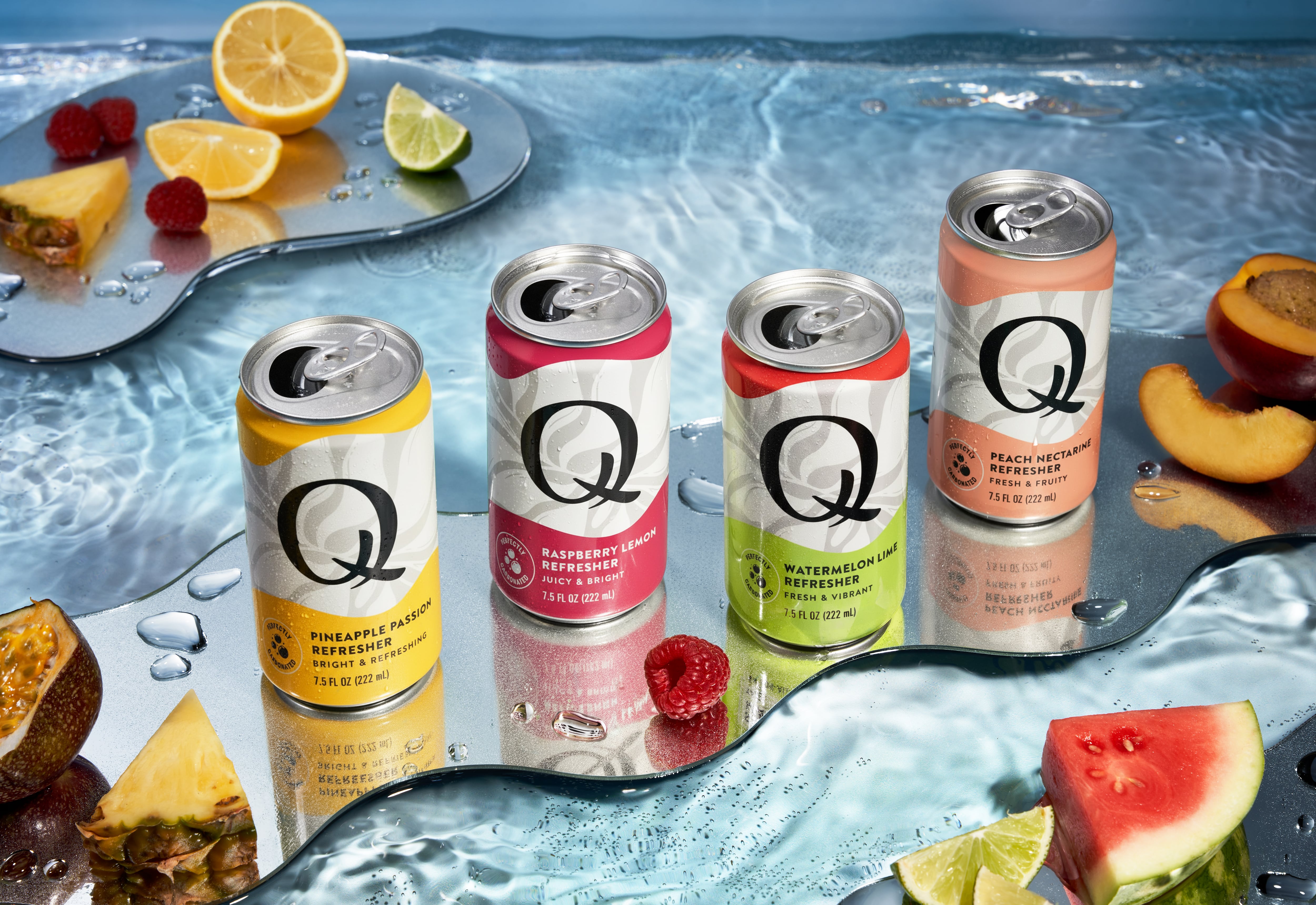 Cans of Q Refreshers in assorted flavours arranged on a table.