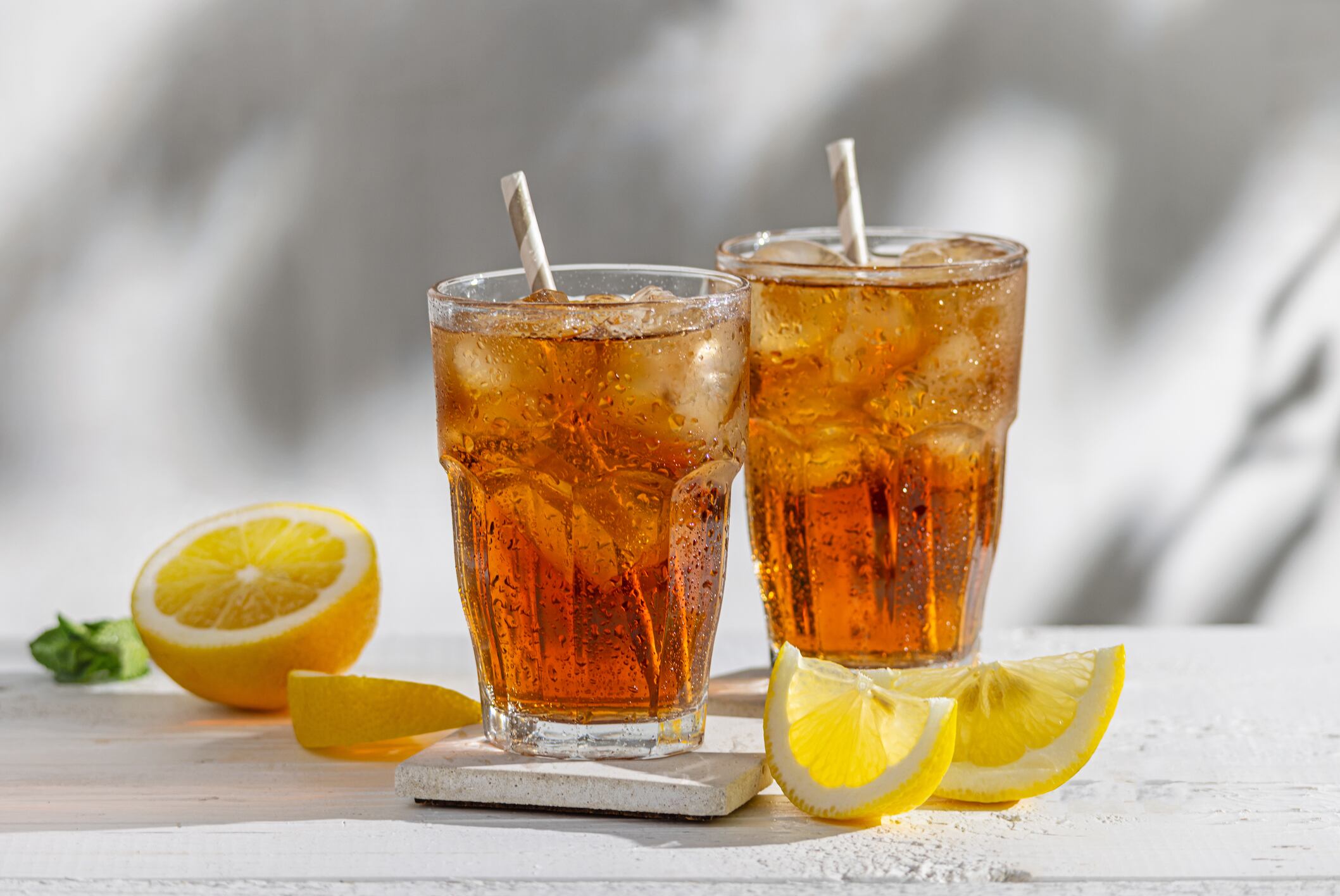 two glasses of ice tea on sunny white wood table