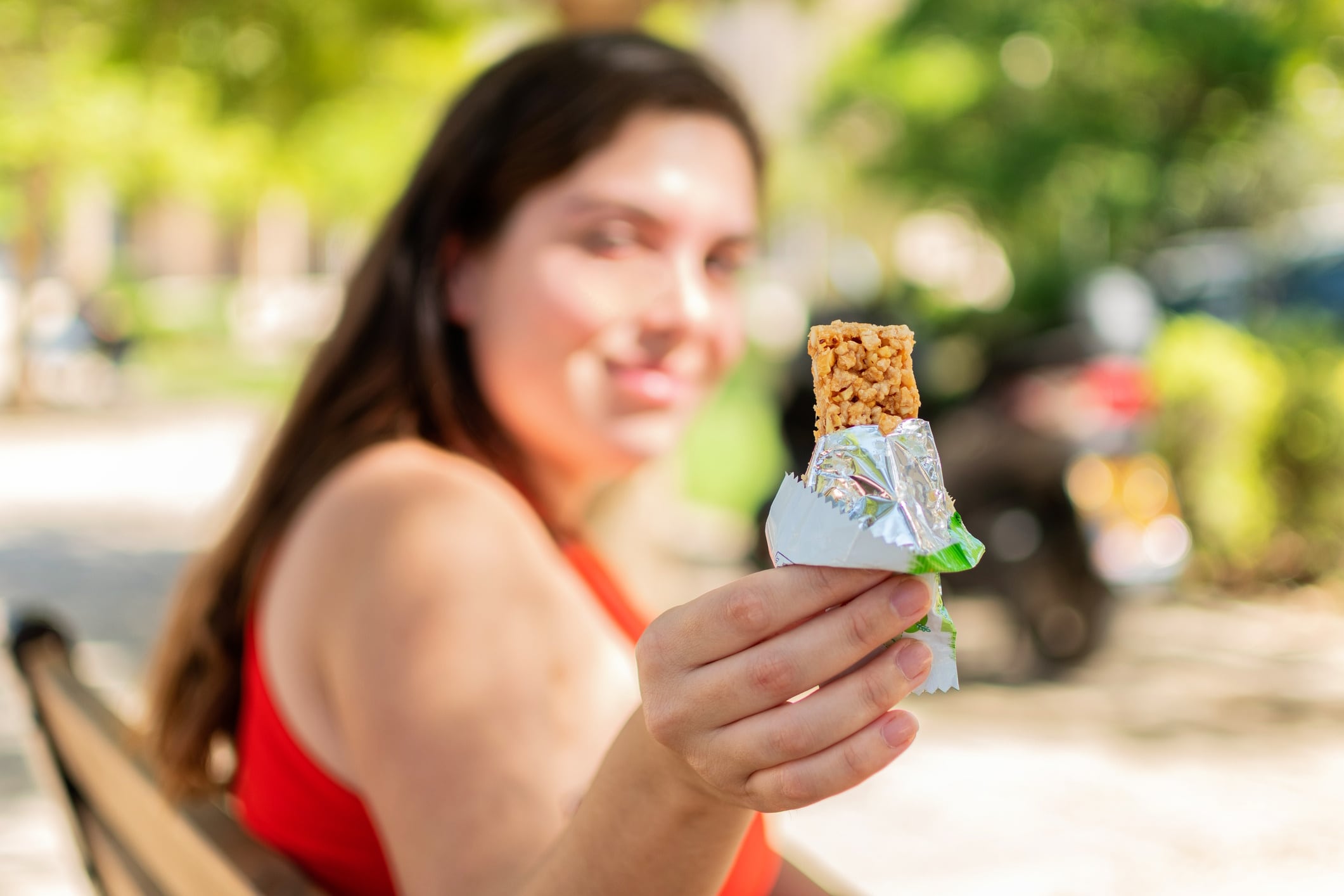 Lady sitting on park bench with healthy snack bar