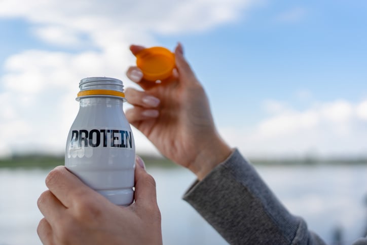 Woman's hands opening a bottle of protein drink, promoting healthy nutrition and fitness