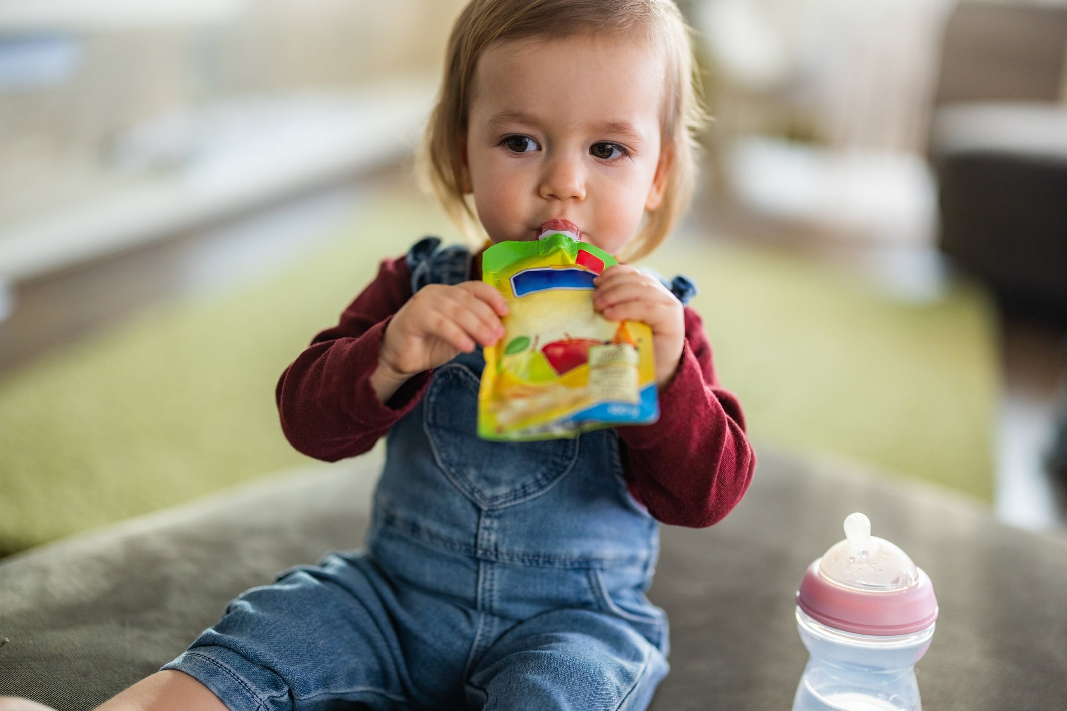 Little girl eating fruit puree from pouch.