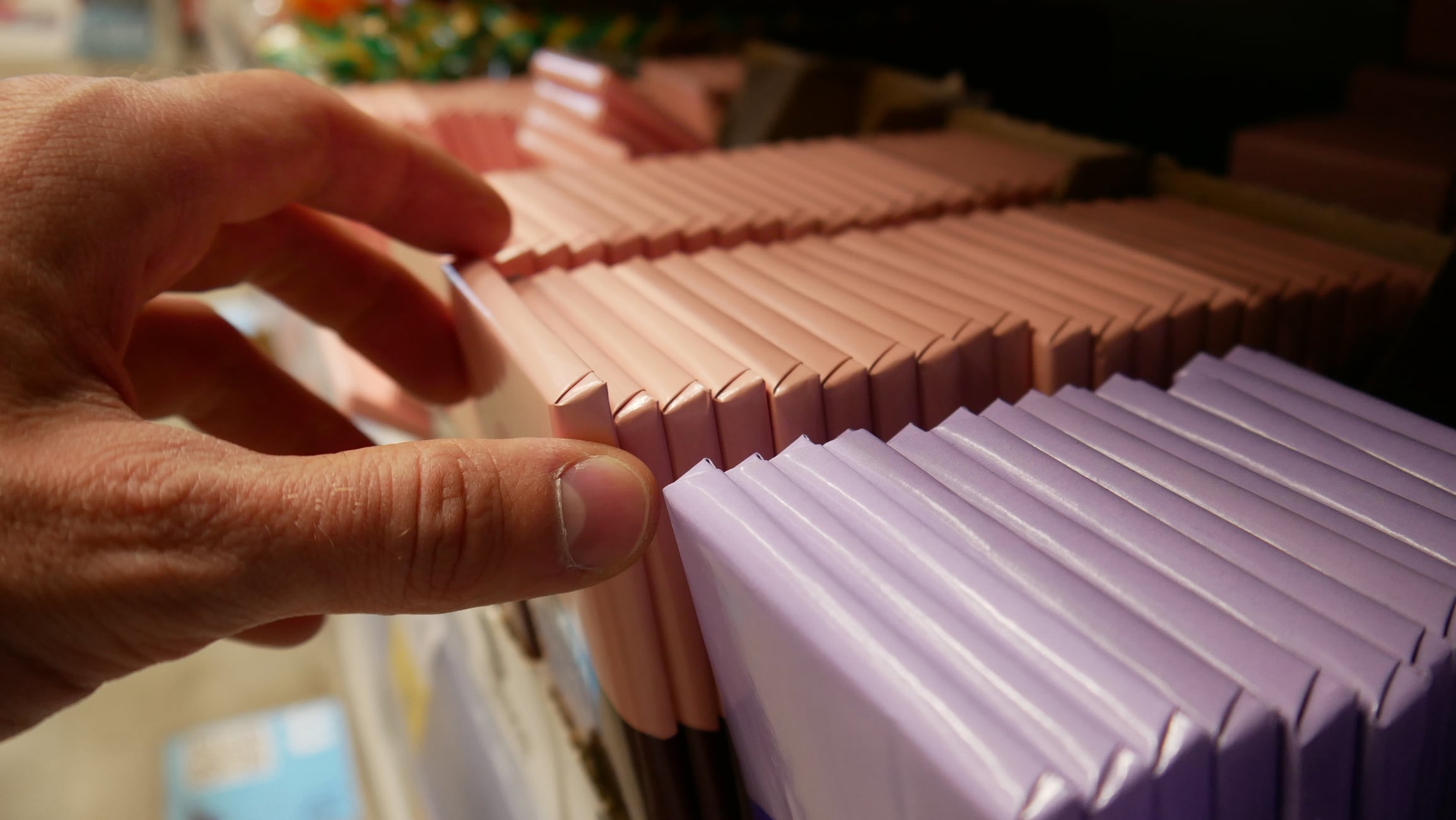 A buyer's hand picking up a chocolate bar in a supermarket