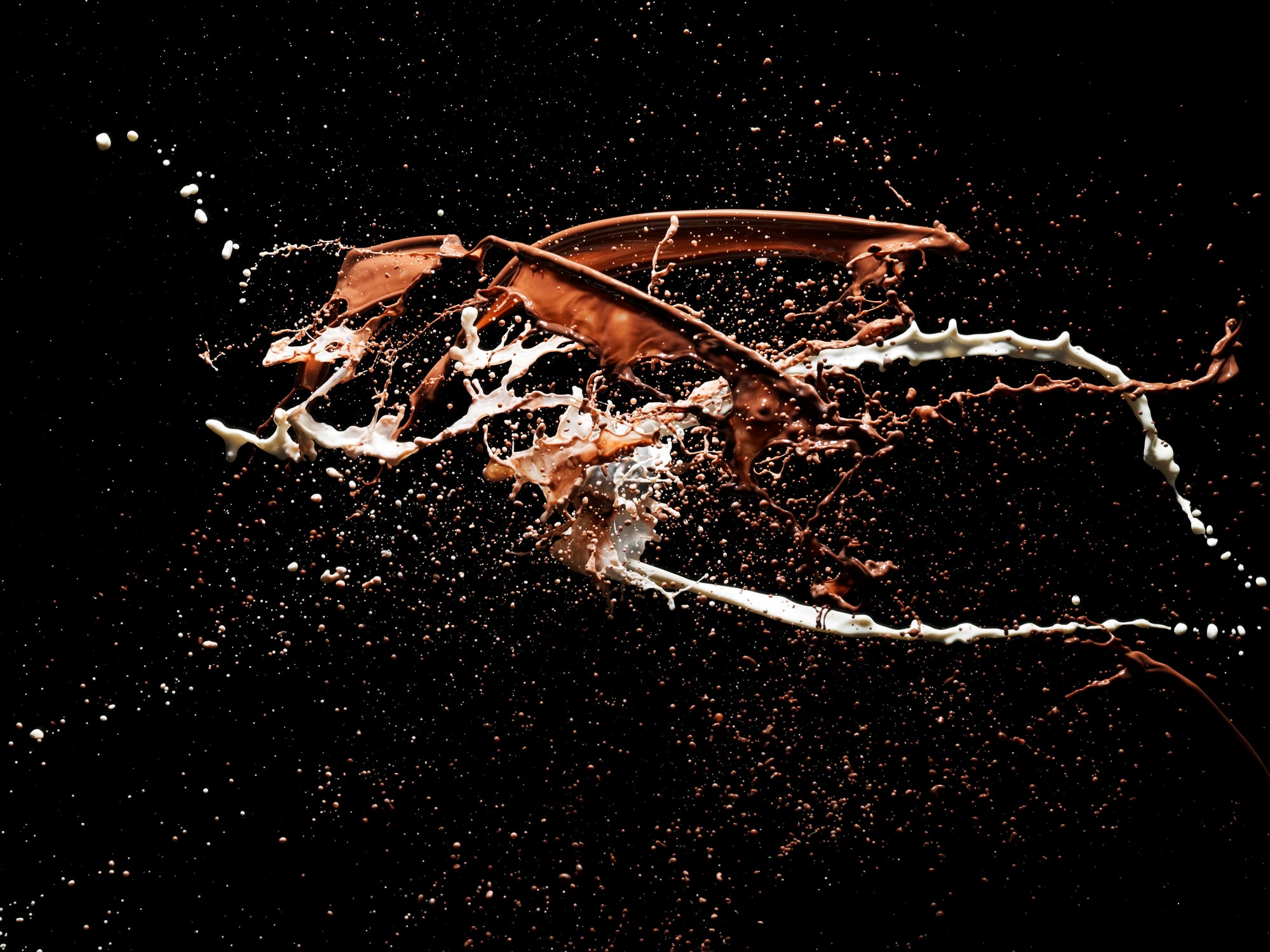 Four bright coloured liquids splashing together, shot on a black backdrop