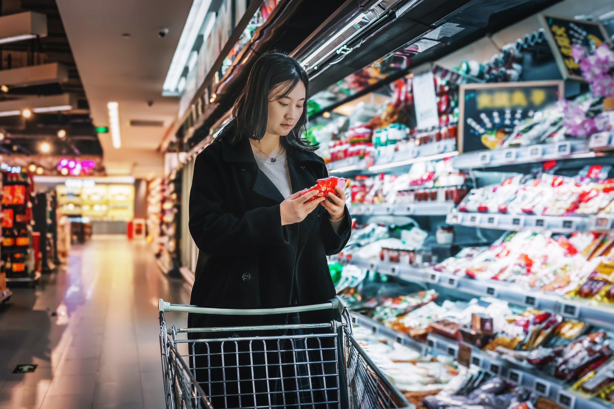 Young Asian women shopping in supermarkets, selecting fresh organic vegetables and fruits