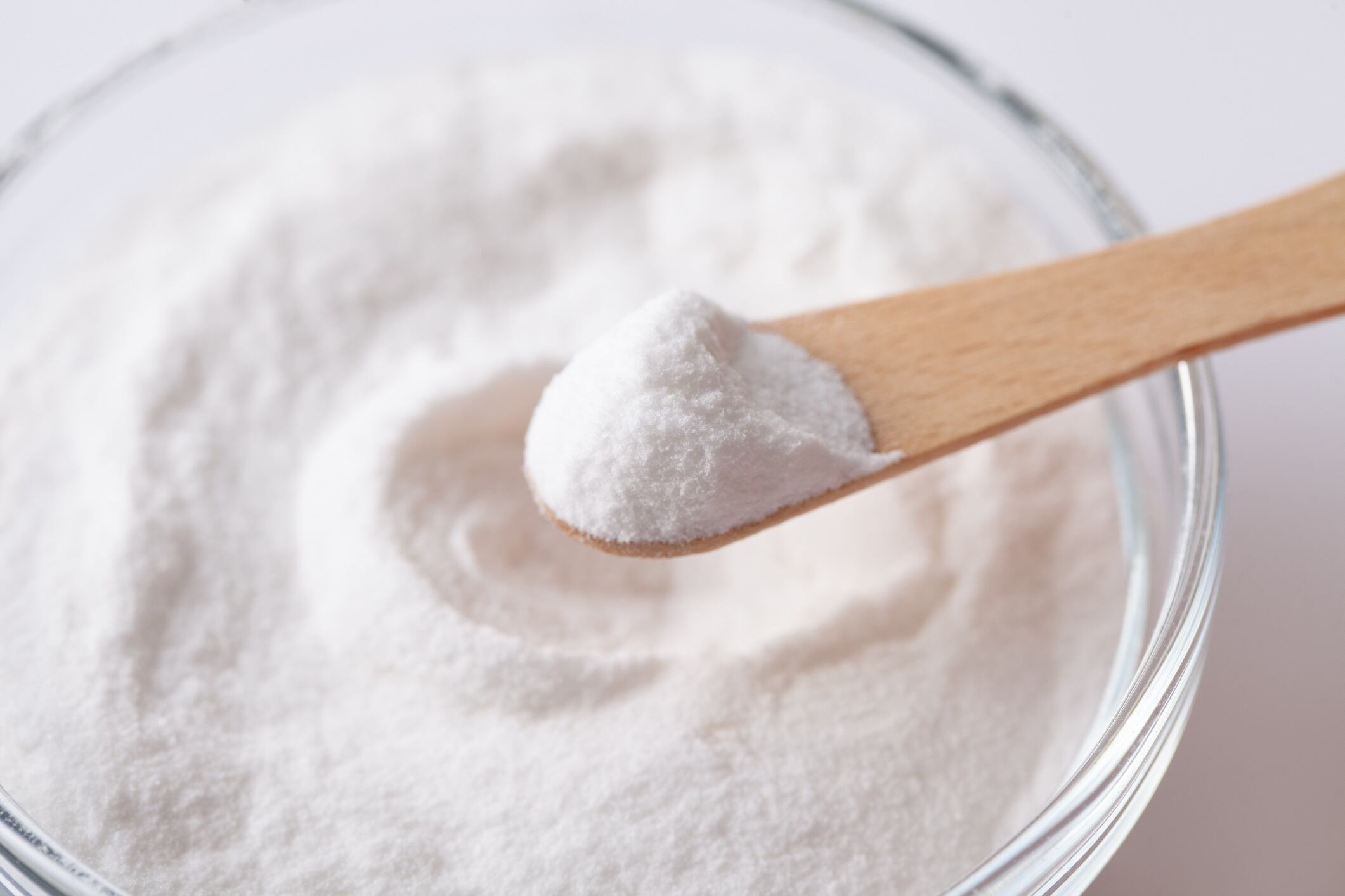 Chemical powder on a wooden spoon aspartame E951 over a bowl