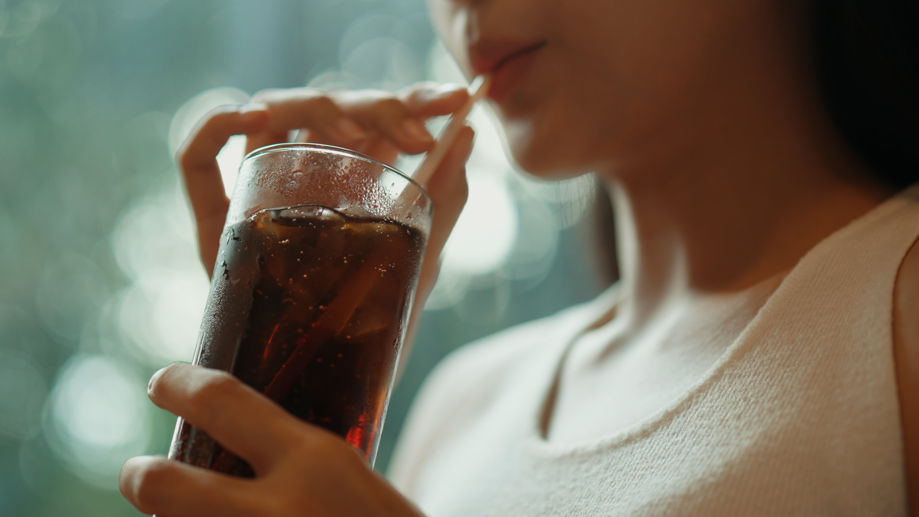 Close-up of a woman enjoying a refreshing glass of cola.