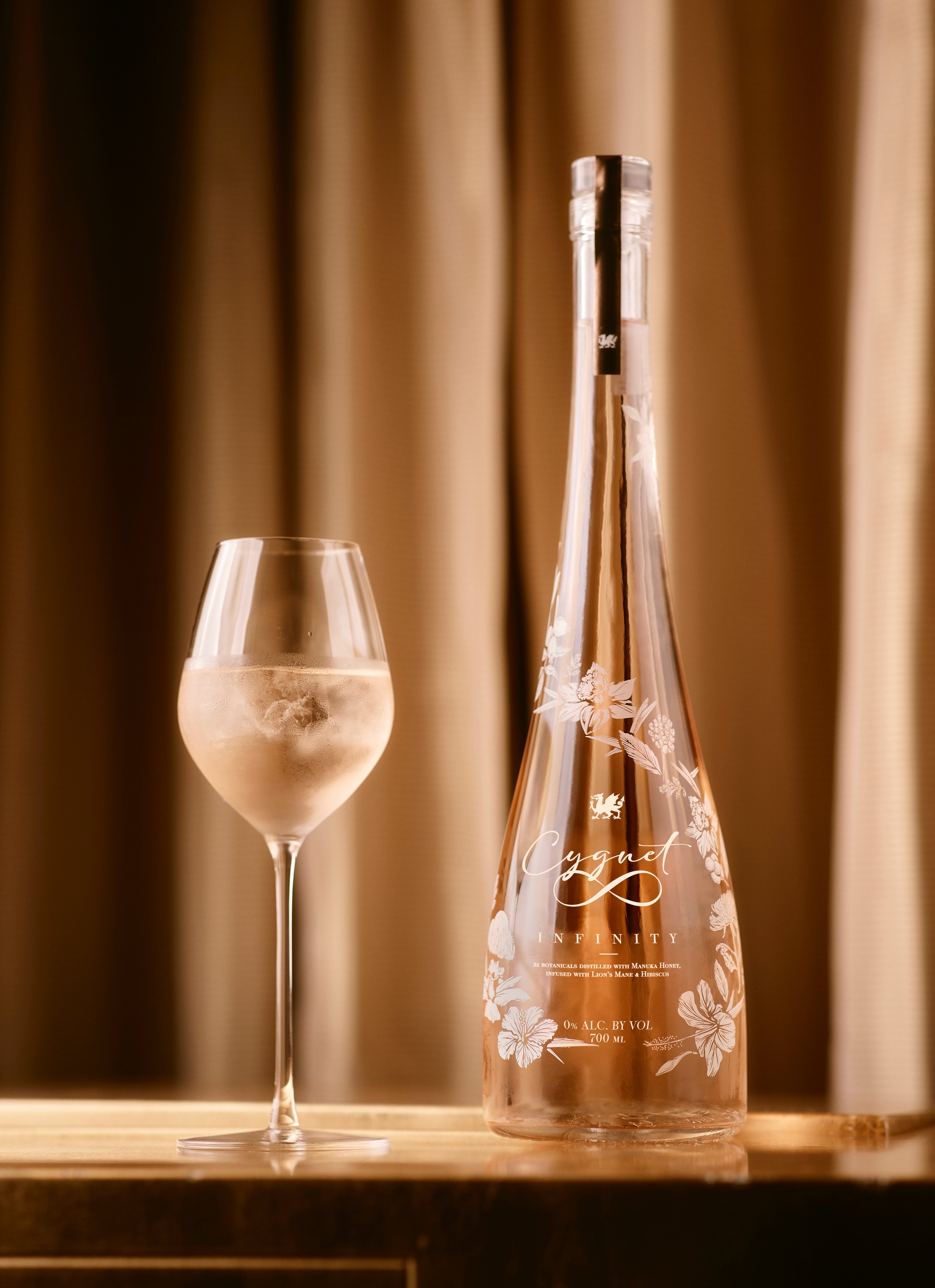 A wine glass beside an elegant shaped bottle of Cygnet Infinity non-alcoholic spirit.