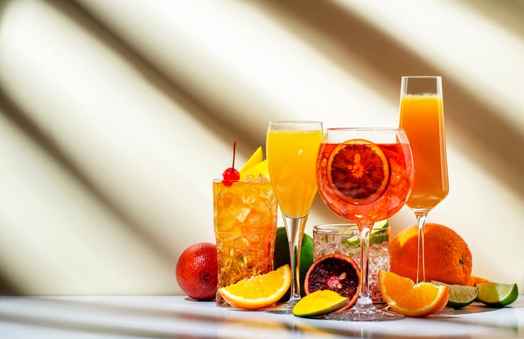 Summer fruit and citrus cocktails for party, low alcohol refreshing drinks with wine, champagne and rum. Beige background, hard light, shadow pattern