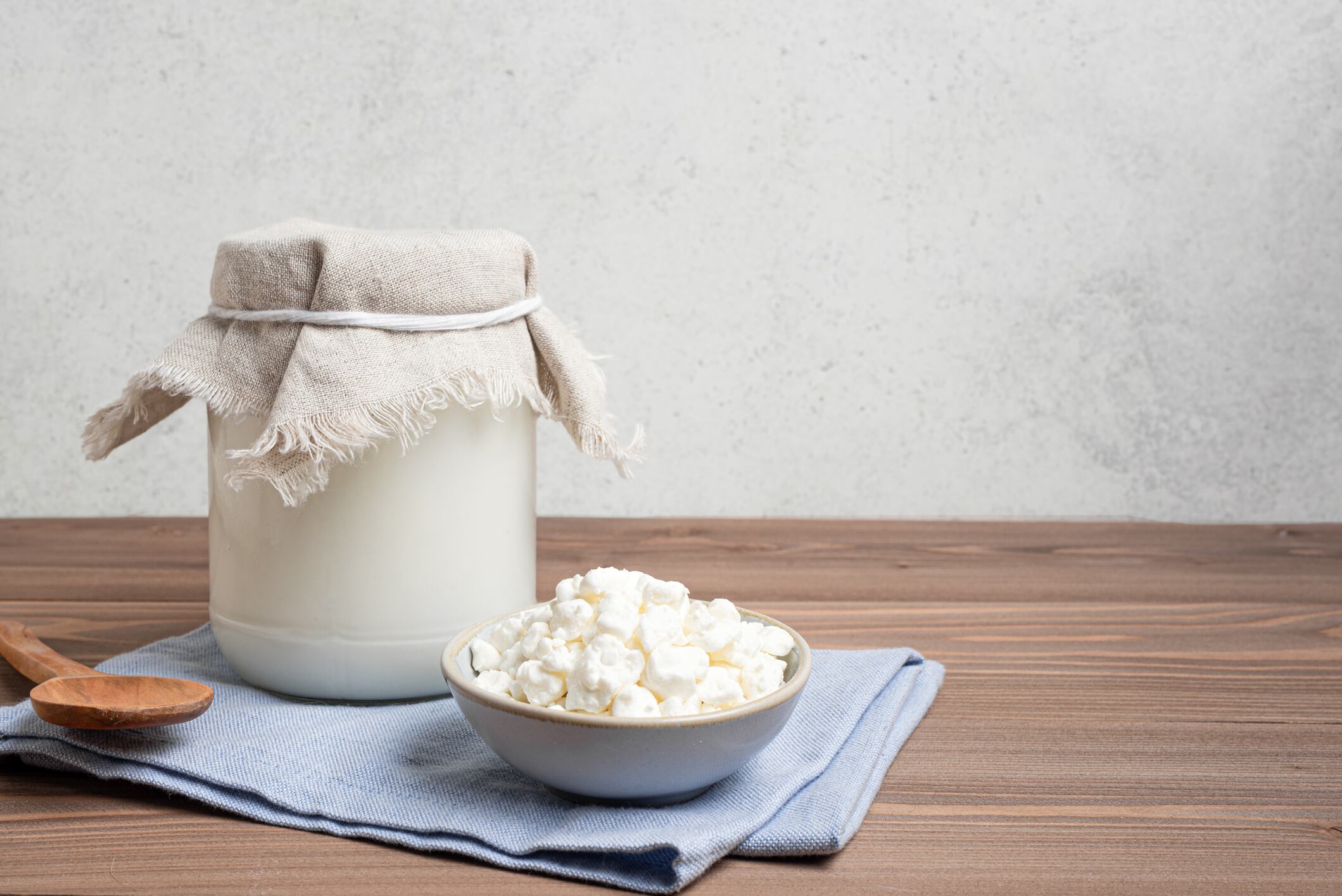 Milk kefir grains and jar of kefir on wooden table, copy space. Preparing healthy fermented  probiotic milk kefir drink.