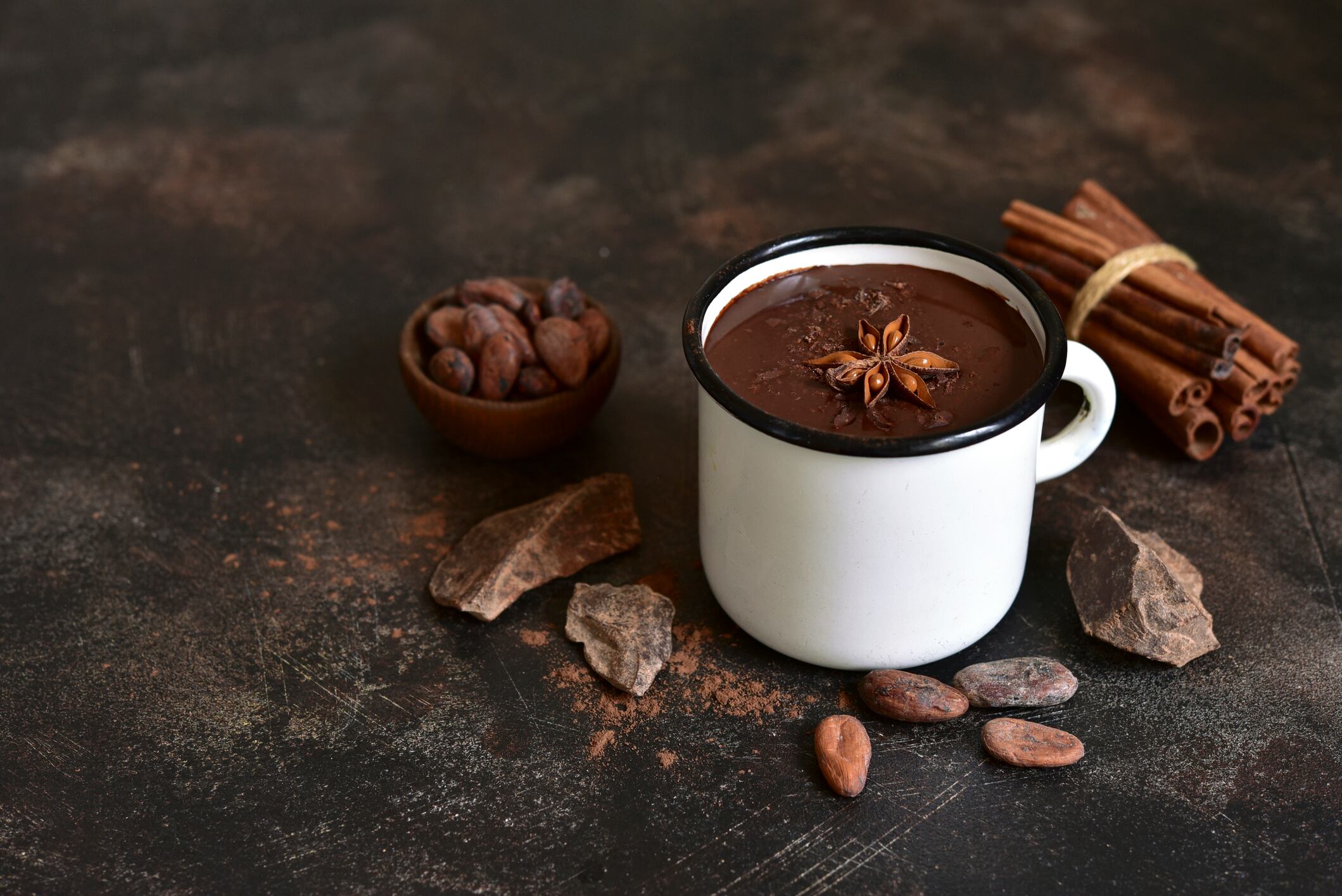 Homemade spicy hot chocolate in a white mug on a dark slate, stone or concrete background.