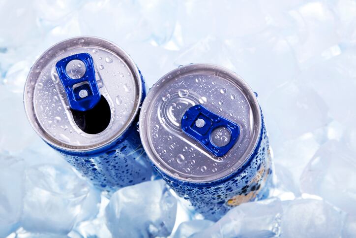 Photo of the top two chilled cans of energy drink in ice.