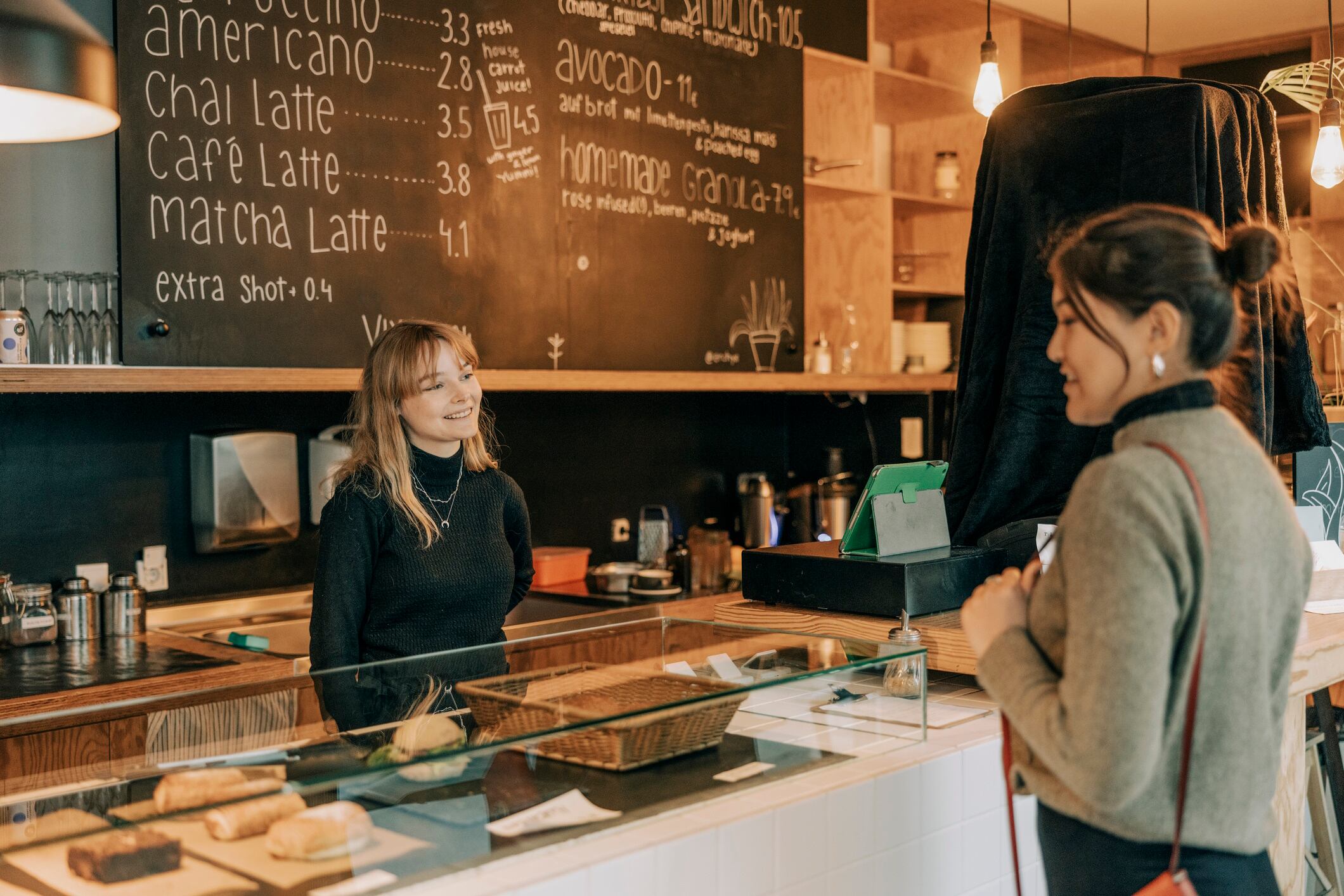 Smiling young woman barista taking order from female customer