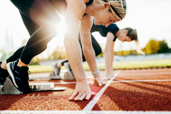 A close up of some women at the starting blocks on an outdoor track before setting off on a run together.